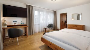 Ein Hotelzimmer mit einem Bett, einem Schreibtisch, einem Stuhl, einem Fernseher und einem Spiegel.
