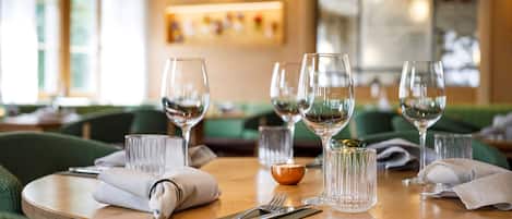 Una mesa de comedor dispuesta con copas de vino, cubiertos y una vela.