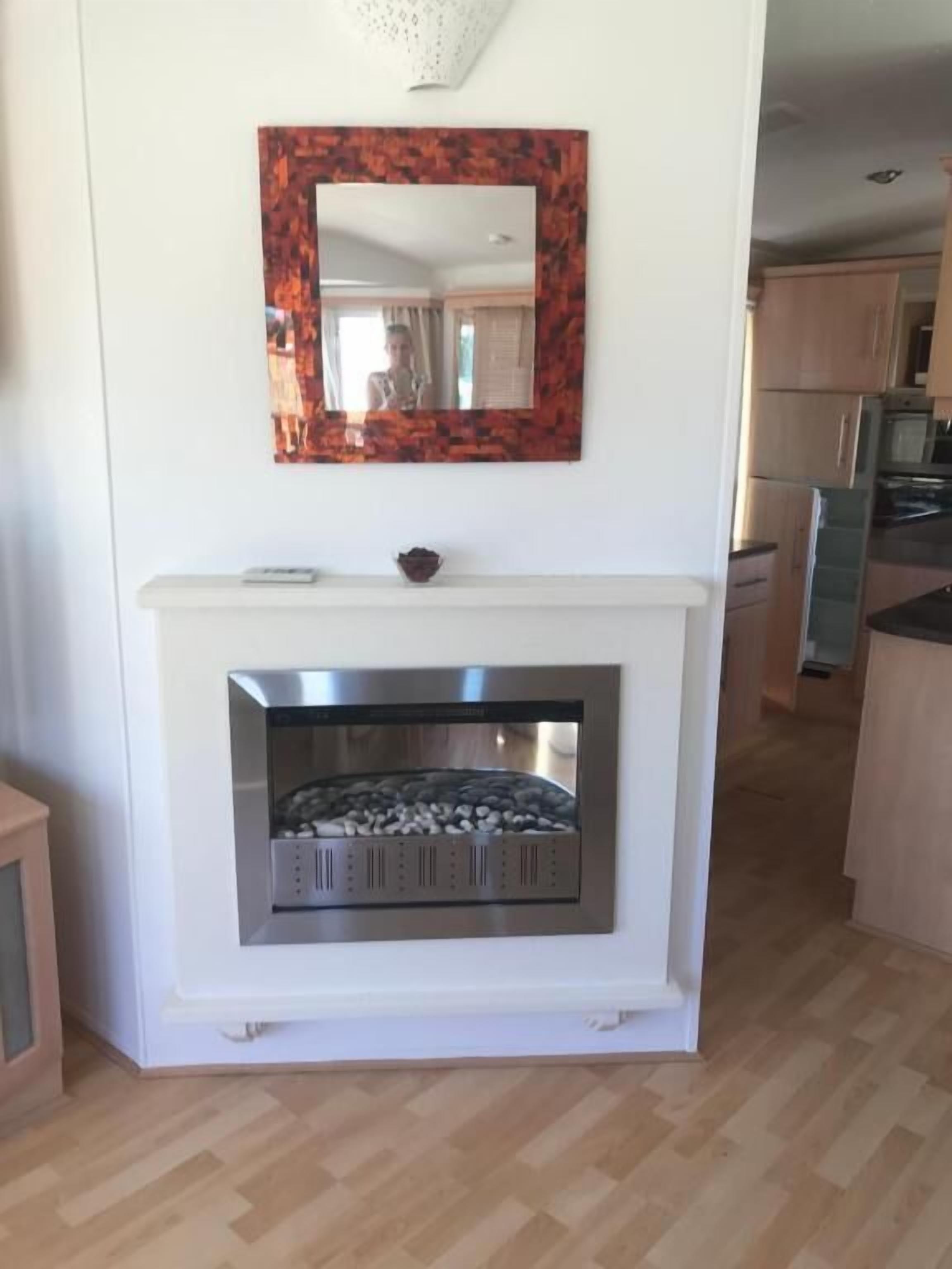 Une cuisine moderne dotée d’une cheminée intégrée, de meubles en bois et d’un mur blanc.