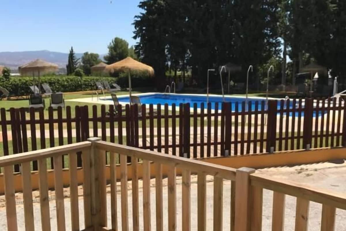 Una terraza de madera con piscina y valla.