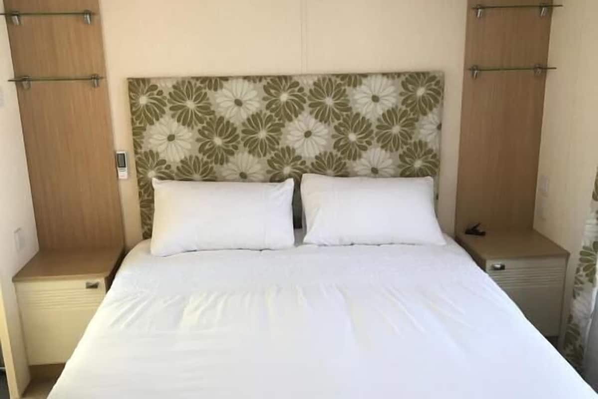 Un dormitorio con una cama grande, dos mesitas de noche y un cabecero estampado con motivos florales.