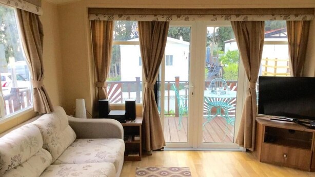 Una sala de estar con un sofá, un televisor sobre un mueble de madera y una alfombra estampada.
