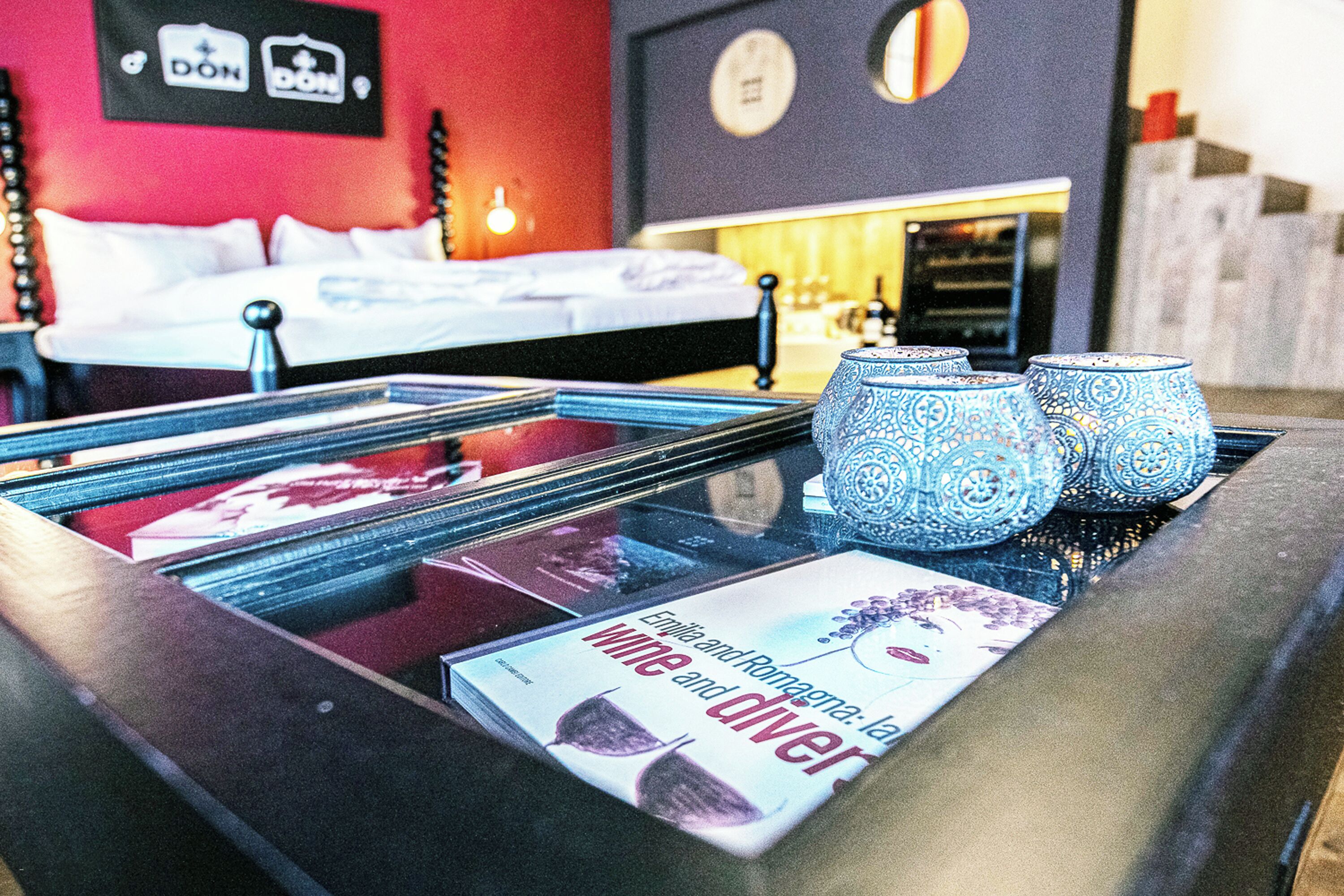 A hotel room with a bed, a bedside table with a magazine, and a decorative vase.