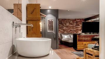 Un baño moderno con una bañera blanca grande, cajas de madera y una pared de ladrillo.