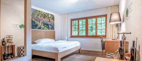 Un dormitorio con cama de madera, un escritorio, una silla y una ventana con cortinas.