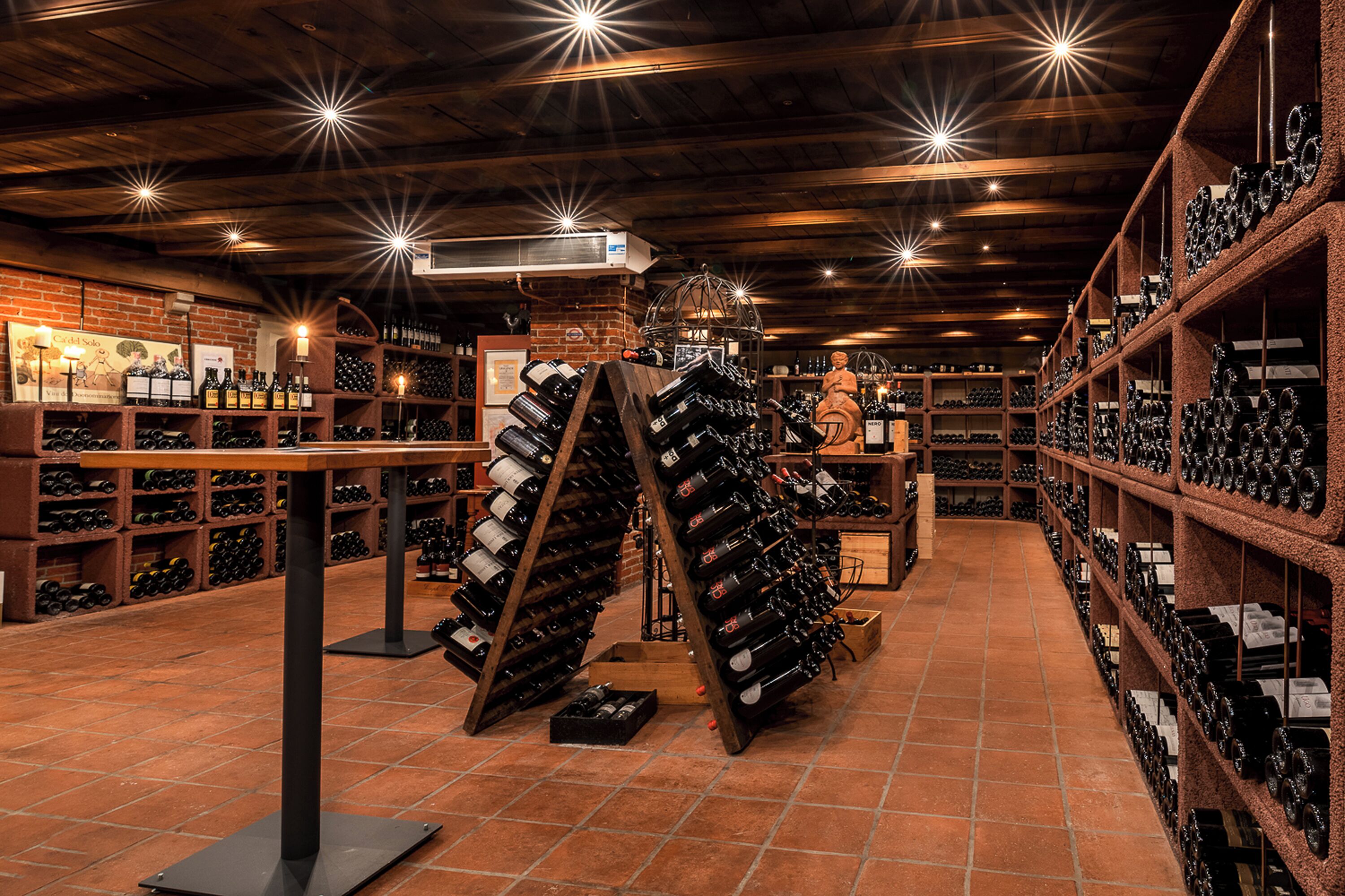A wine cellar with wooden racks and shelves filled with wine bottles.