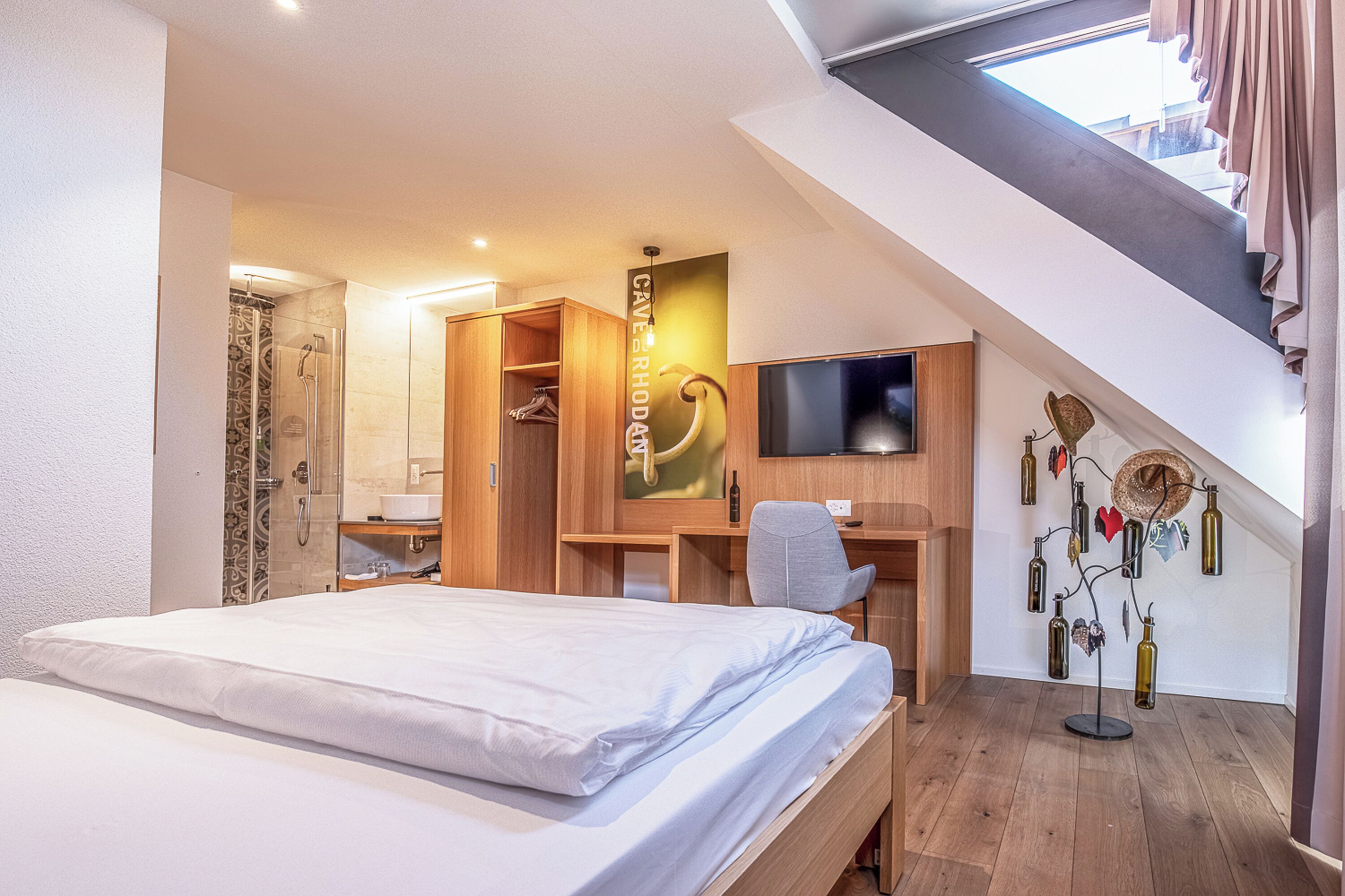 A modern hotel room with a bed, desk, and TV.