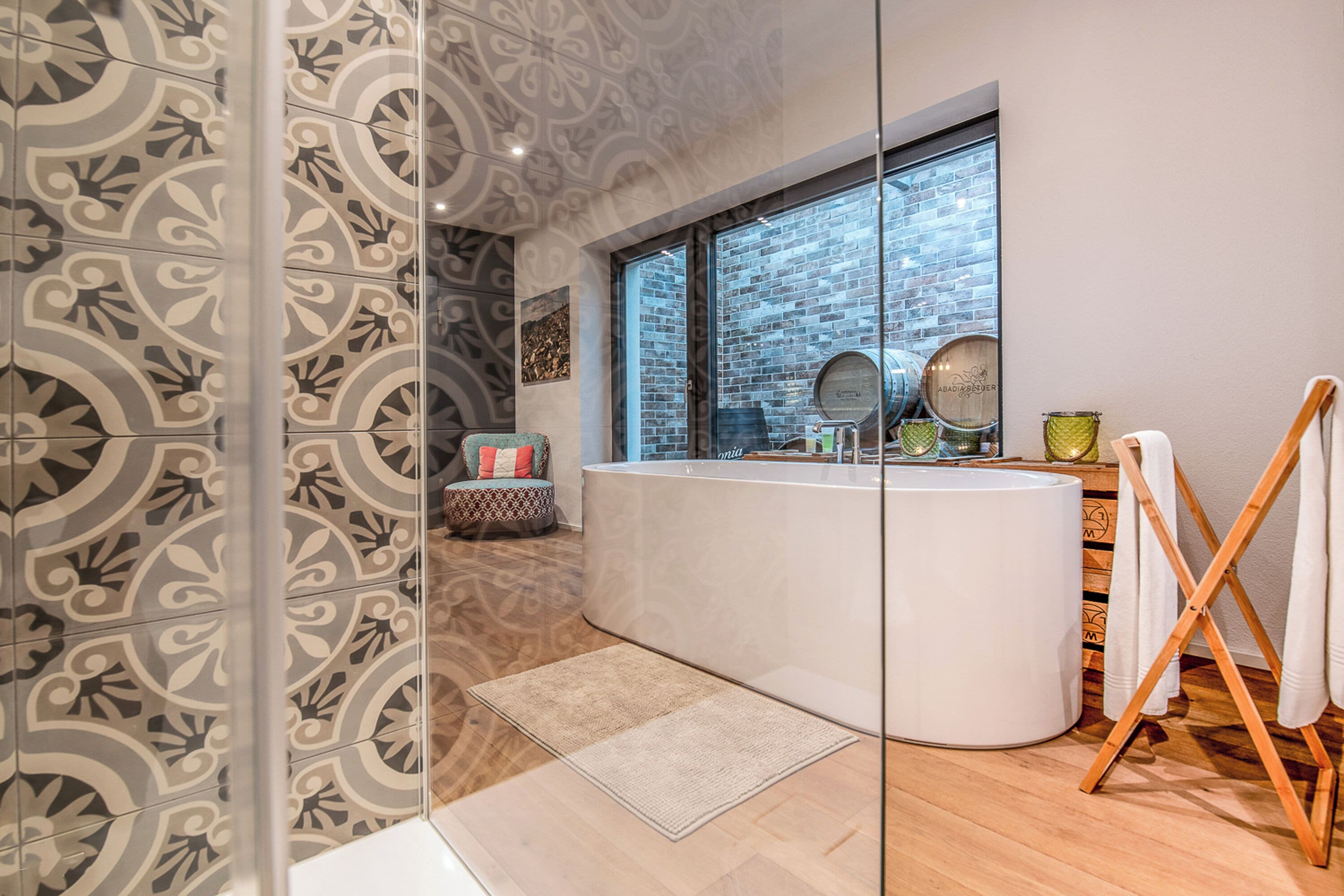 A modern bathroom with a large bathtub, a glass shower enclosure, and a window with a view of the city.