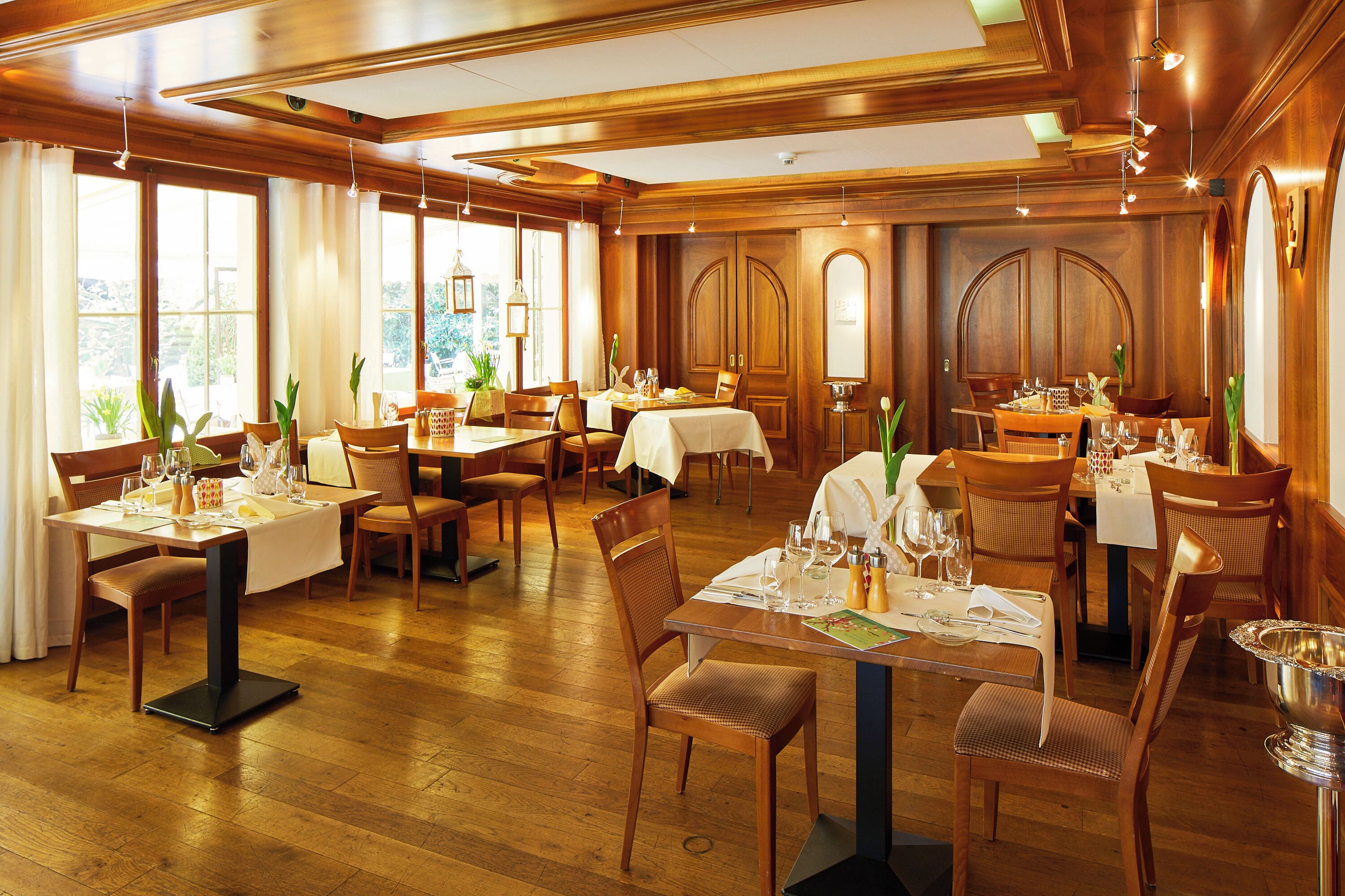 Un restaurante con interiores de madera, varias mesas y sillas.