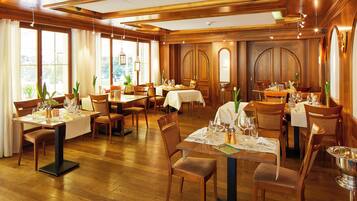 Un restaurante con interiores de madera, varias mesas y sillas.