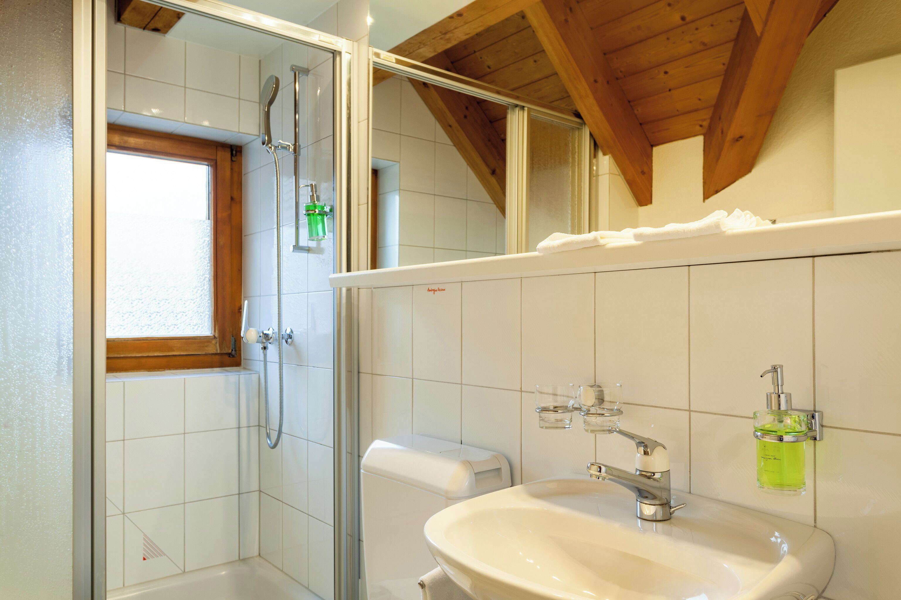 A bathroom with a shower, toilet, sink, and a window.
