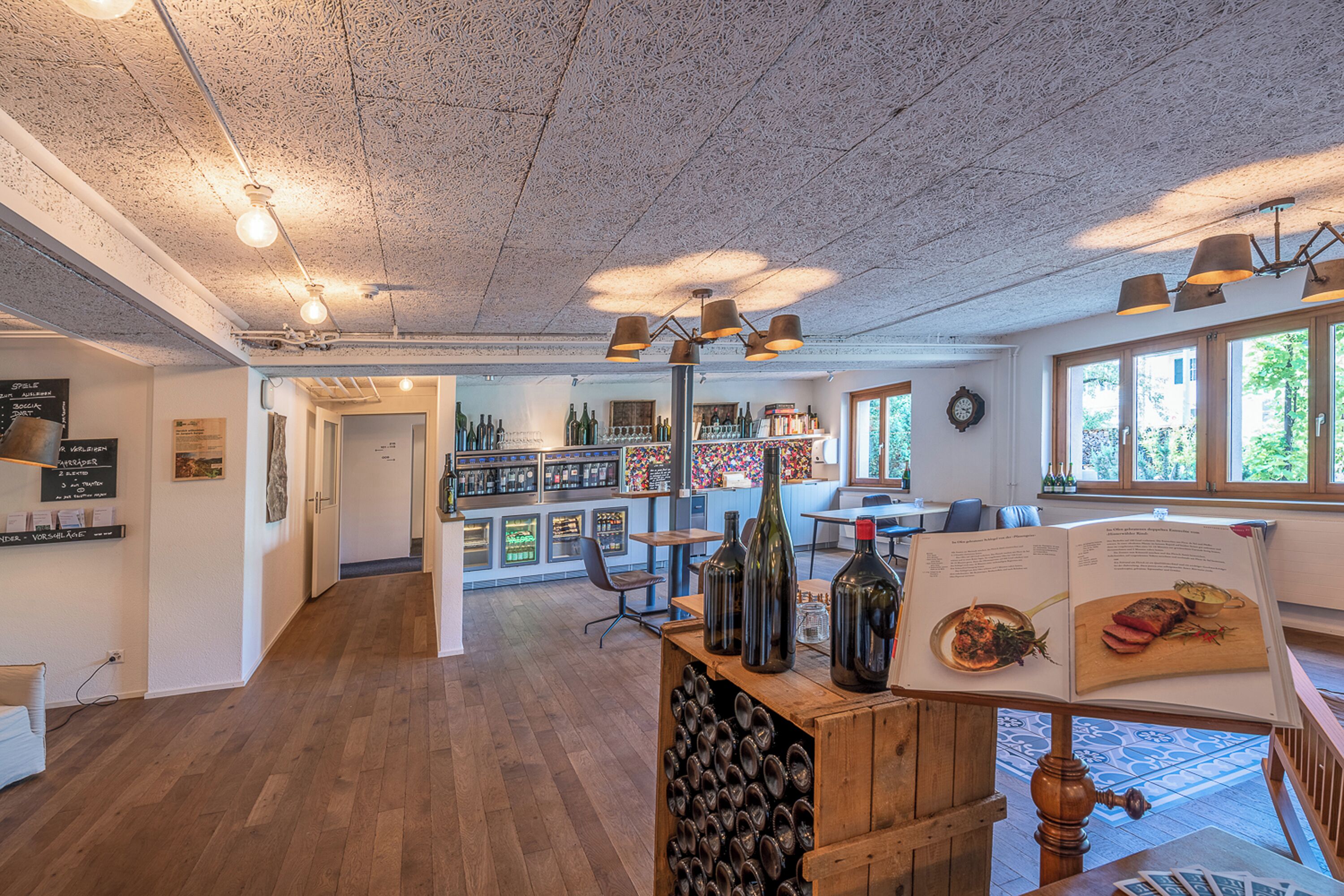A restaurant interior with wooden floors, a wine display, and a menu on a stand.