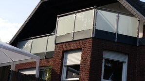 Un bâtiment à deux étages avec une façade en briques, de grandes fenêtres équipées de stores et un auvent blanc.