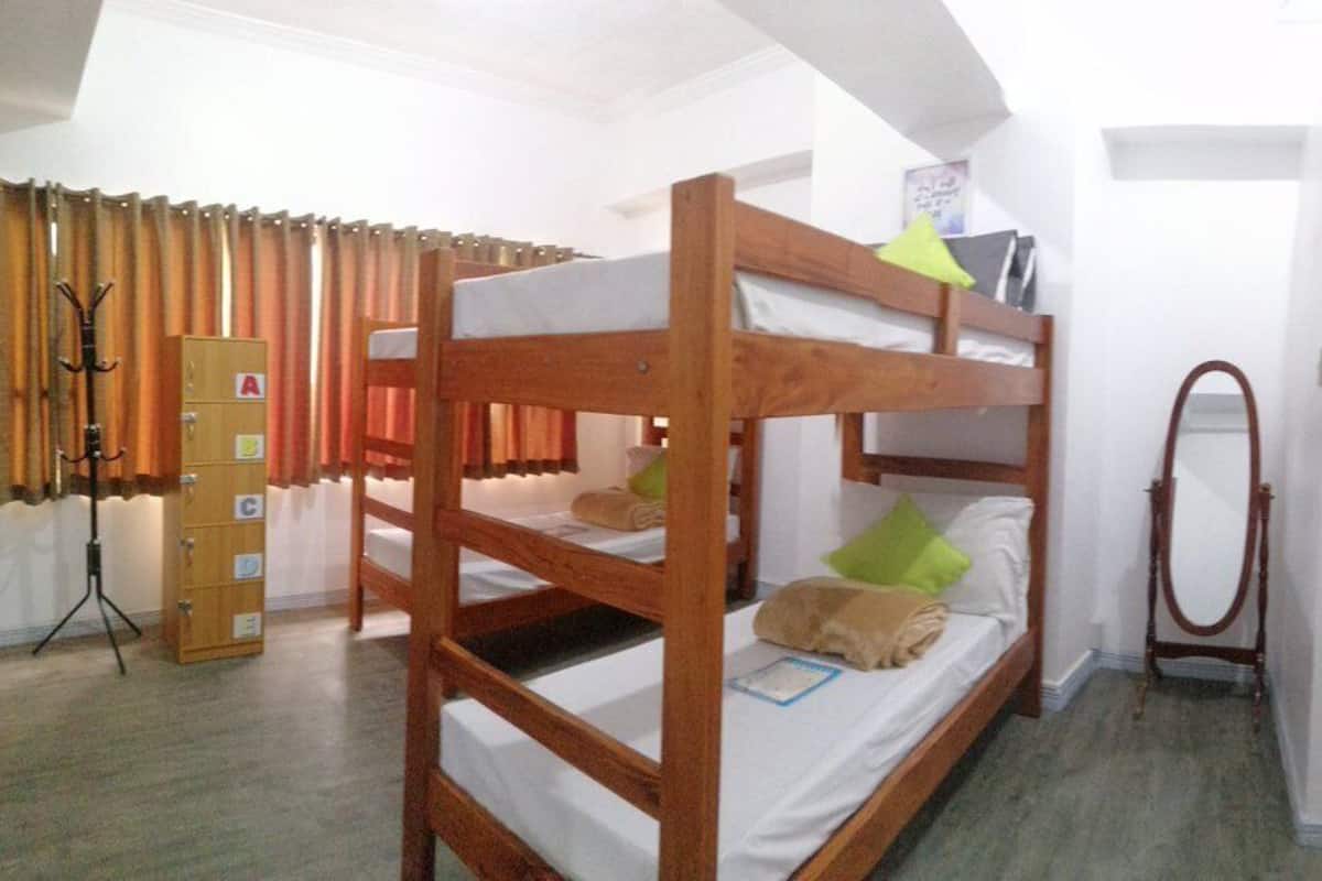 Una habitación pequeña con literas, un kitchenette reducido y una puerta que da a otra habitación.