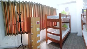 A dormitory room with bunk beds, a coat rack, a cabinet with drawers, and a small kitchenette. - V - Rooms Hostel - Adults Only (Makati)