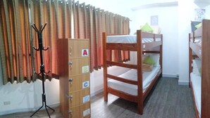 A room with bunk beds, a coat rack, a cabinet with drawers, and a kitchenette area. - V - Rooms Hostel - Adults Only (Makati)