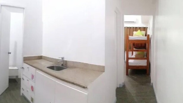 A narrow hallway with a kitchenette area featuring a sink and cabinets, leading to a room with a bunk bed. - V - Rooms Hostel - Adults Only (Makati)