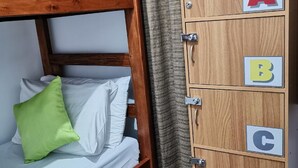 A bunk bed with a green pillow and a wooden cabinet with alphabet blocks. - V - Rooms Hostel - Adults Only (Makati)
