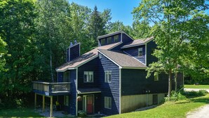 Une maison à deux étages avec un balcon, une véranda et un garage.