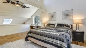 Une chambre à coucher avec un grand lit, un ventilateur de plafond, un bureau et deux lampes fixées au mur.