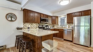 Une cuisine moderne avec des meubles en bois, un réfrigérateur en acier inoxydable et un îlot central doté de tabourets.