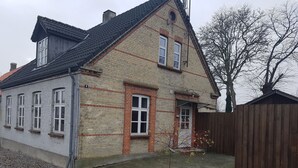 Una casa de dos pisos con fachada de ladrillo, techo de tejas y valla de madera.