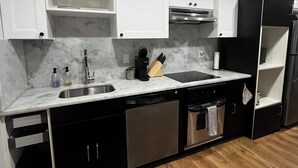 Une cuisine moderne avec des meubles blancs, des appareils en acier inoxydable et un tapis à motifs.