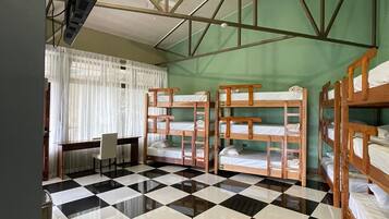 Un dormitorio con literas, piso a cuadros, un escritorio con silla y una ventana con cortinas.