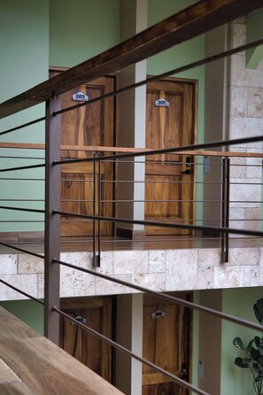 A multi-level wooden staircase with metal railings and doors numbered 201, 202, and 203. - Hotel Mi Linda Tierra (Quesada)