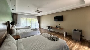 Hotellihuone, jossa on kaksi sänkyä, työpöytä, tuoli, televisio ja kattotuuletin.