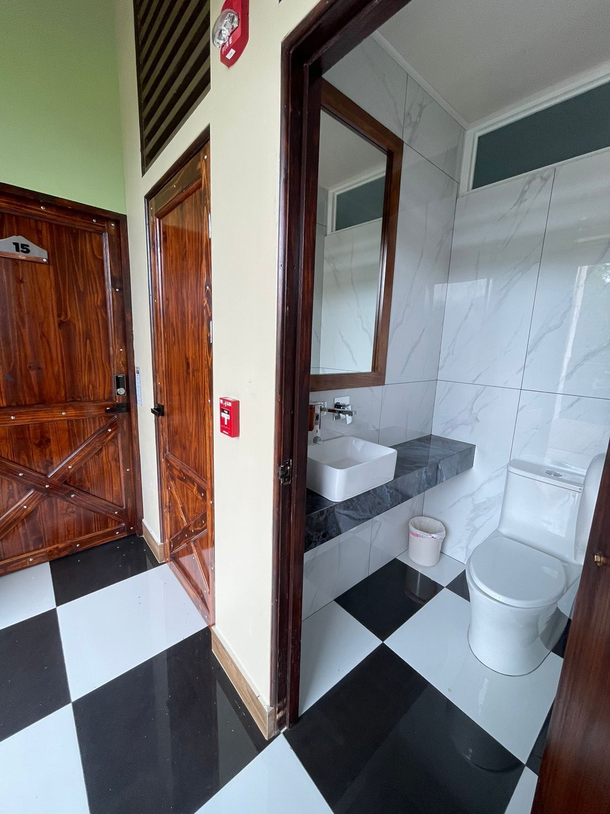 A bathroom with a checkered floor, a sink, a toilet, and a mirror.