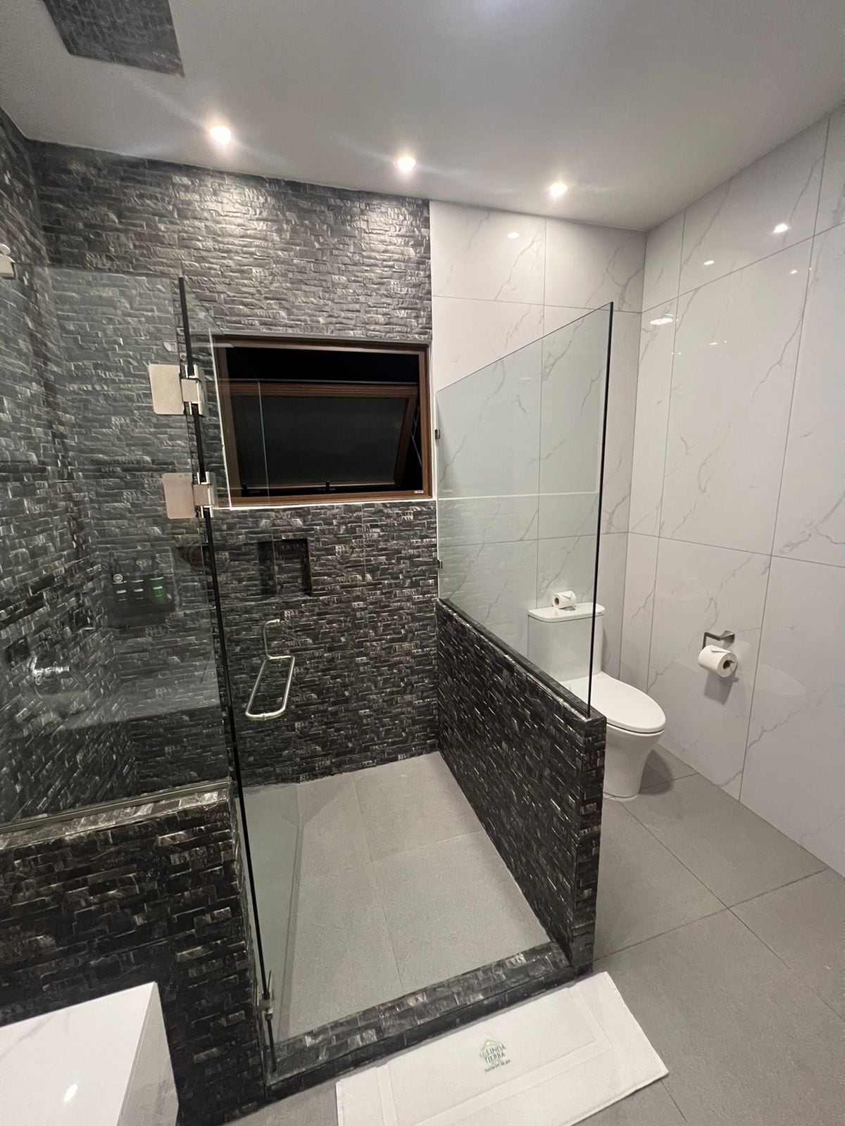Un bagno moderno con doccia a vetro, un water e un lavandino.