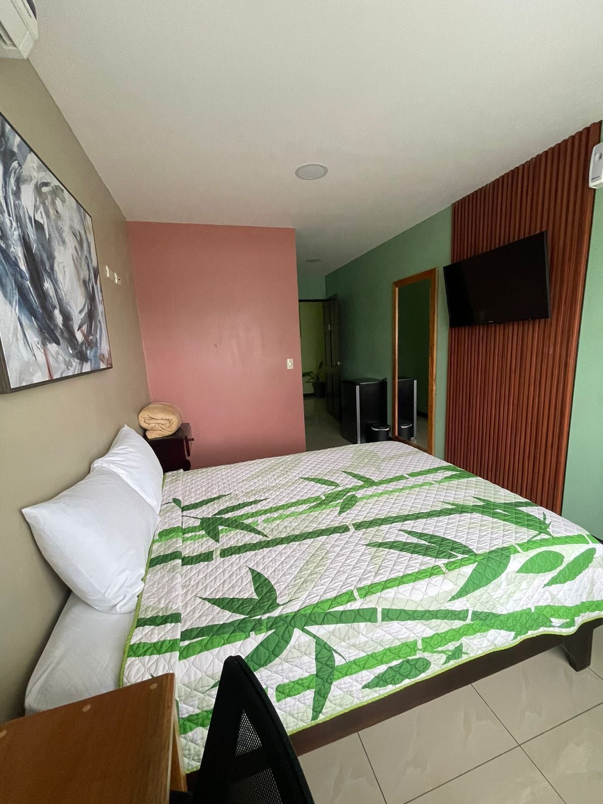 Une chambre d’hôtel avec un lit, une télévision et un tableau accroché au mur.