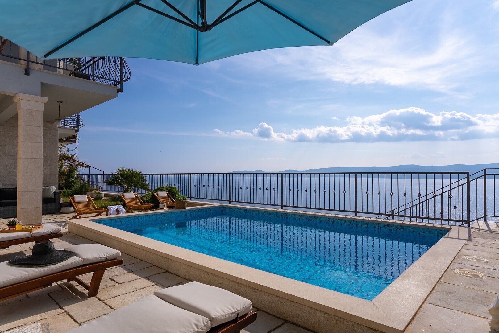 A rectangular pool with a clear blue water, surrounded by lounge chairs and a pergola.