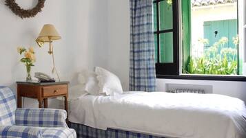 Un dormitorio con cama, mesita de noche, lámpara y silla.