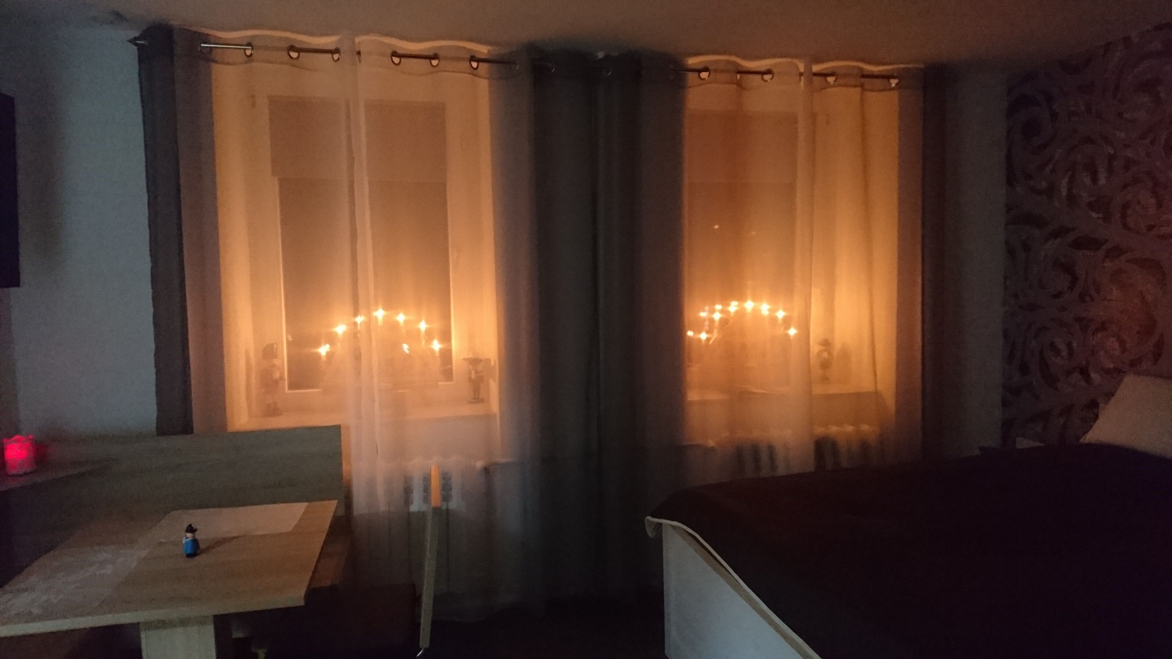 Ein Hotelzimmer mit Bett, Tisch, Stuhl und einem Vorhangfenster.