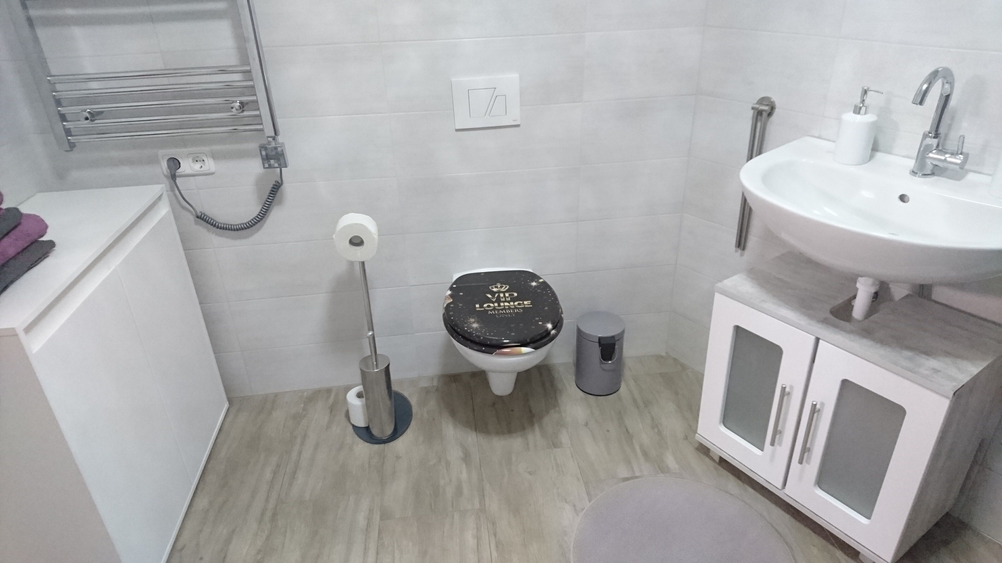 A bathroom with a toilet, bidet, sink, and cabinet.