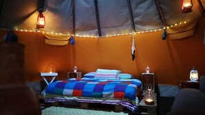 Ein gemütliches Zelt mit einem Bett, zwei Nachttischen und Lichterketten.