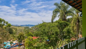 A view of a resort with a pool area, lush greenery, and distant hills. - Estância Solazer (Santa Isabel)