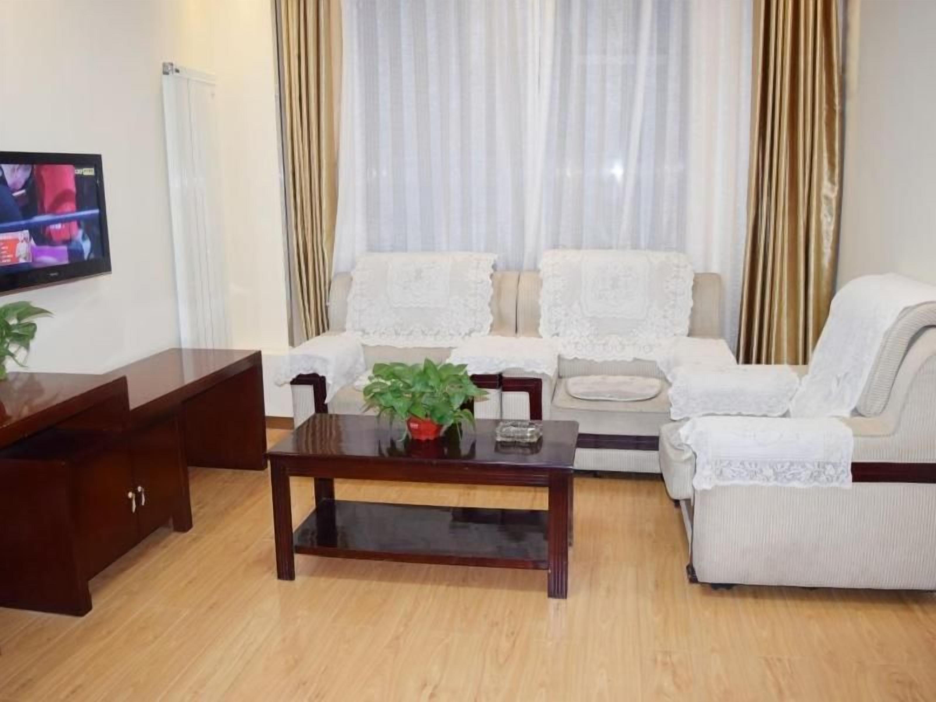 Una sala de estar con un conjunto de sofá, una mesa de centro con una planta y un televisor montado en la pared.