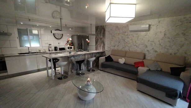 A modern kitchen with a central island, bar stools, a glass coffee table, and a sofa with cushions. - Your little paradise;) (ESPONDEILHAN)