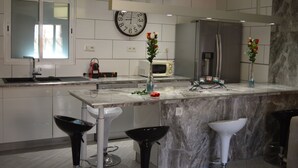 A modern kitchen with a marble countertop, stainless steel appliances, and a clock on the wall. - Your little paradise;) (ESPONDEILHAN)