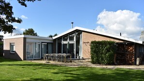 Ett modernt hus med en uteplats, en fasad av tegel och en stor glasdörr.