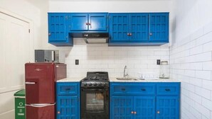 Cozinha com armários azuis, geladeira vermelha e fogão preto.