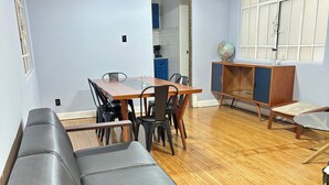 Uma sala de estar com sofá, mesa de jantar, cadeiras e um arm ário.