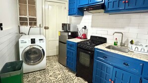 Uma cozinha compacta com armários azuis, máquina de lavar, geladeira e fogão.