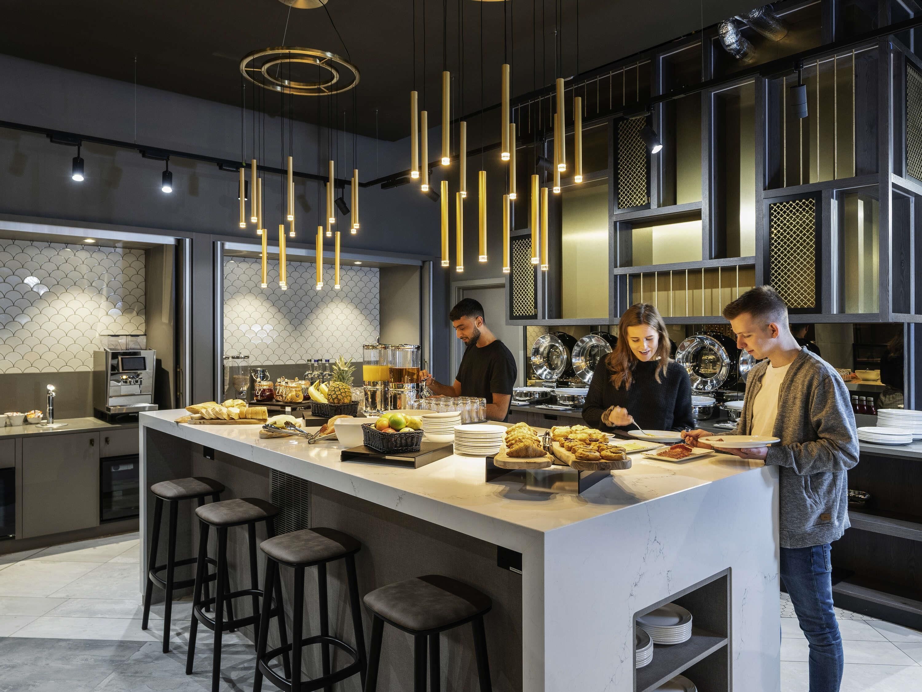 A modern kitchen with a central island, bar stools, and hanging pendant lights.