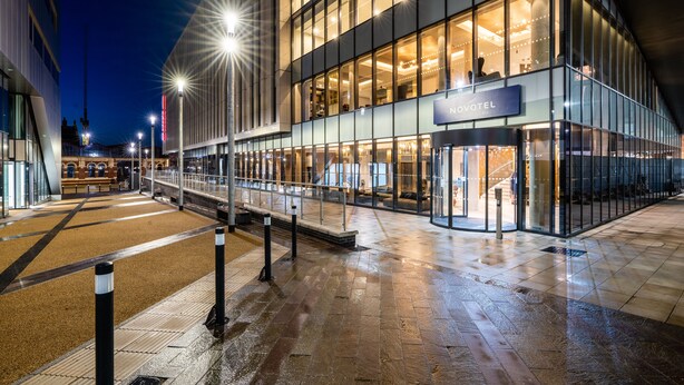 A modern hotel exterior with a glass facade, a covered entrance, and a well-lit outdoor area. - Novotel Leicester (Leicester)