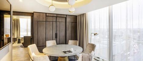 A modern dining area with a round table, six chairs, and a city view through large windows.