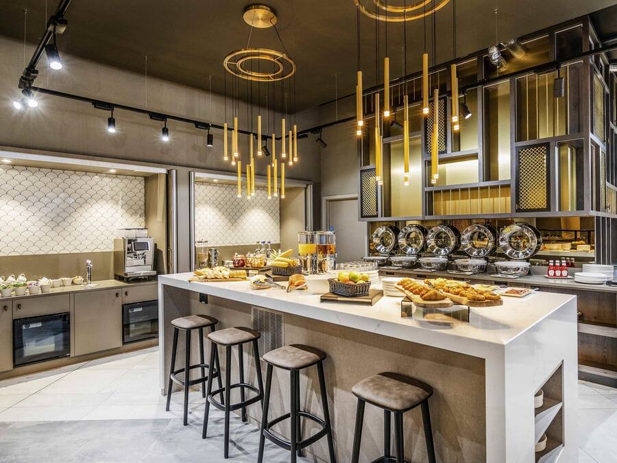 A modern kitchen with a central island, bar stools, and a variety of breakfast items.